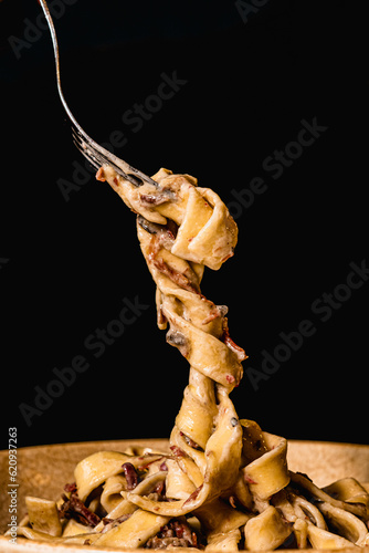 Espaguetis carbonara enrollados con el tenedor con fondo negro