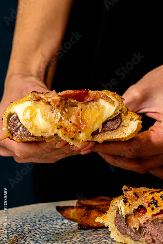 hamburguesa cogida por una persona, con mucho queso y bacon 