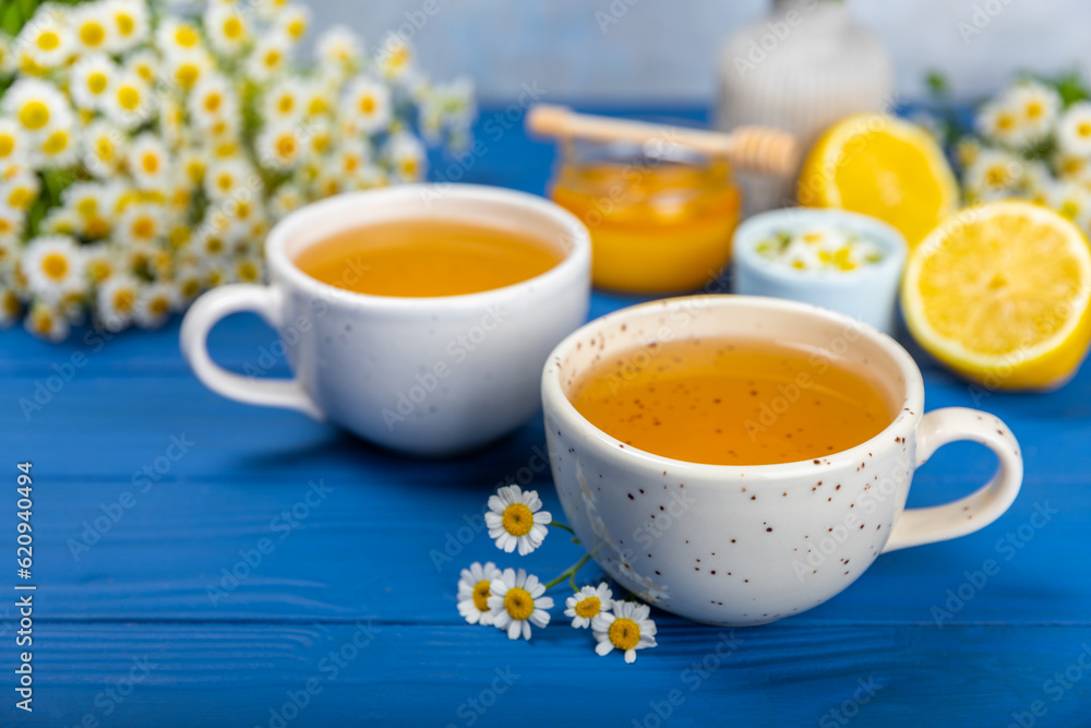 Chamomile herbal tea with flower buds on a blue wooden table and a bouquet of chamomile. Useful herbal, soothing drinks and natural healer concept. Immunity tea.Close up. Copy space. Chamomile herbal tea with flower buds on a blue wooden table and a bouquet of chamomile. Useful herbal, soothing drinks and natural healer concept. Immunity tea.Close up. Copy space.