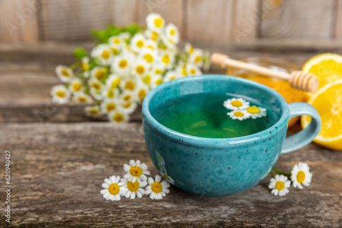 Chamomile herbal tea with flower buds  honey and lemon on a brown wooden table and a bouquet of chamomile. Useful herbal  soothing drinks and natural healer concept. Immunity tea.Close up. Copy space.