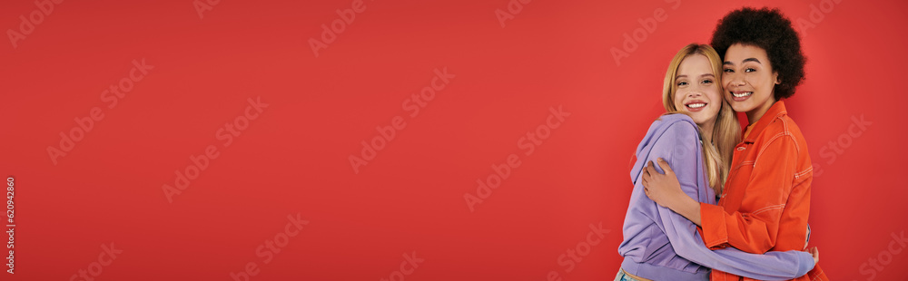 cultural diversity, cheerful multicultural women hugging while looking at camera on coral background, blonde and brunette, diverse friends, sisterhood, friendship goals, studio shot, banner cultural diversity, cheerful multicultural women hugging while looking at camera on coral background, blonde and brunette, diverse friends, sisterhood, friendship goals, studio shot, banner