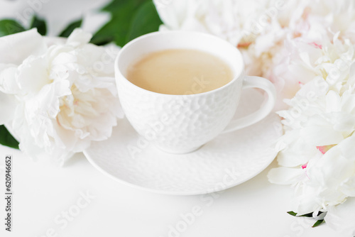Morning coffee cup and white peonies flowers on white background