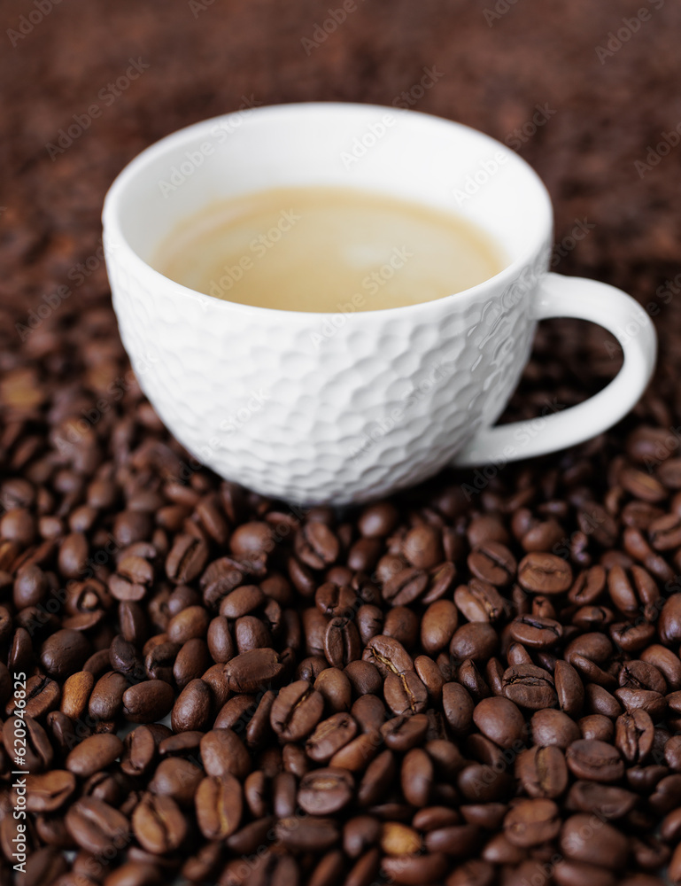 White cup of dark coffee on background from coffee beans