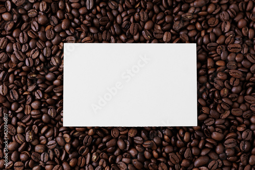 Top view of blank paper card on dark background from coffee beans