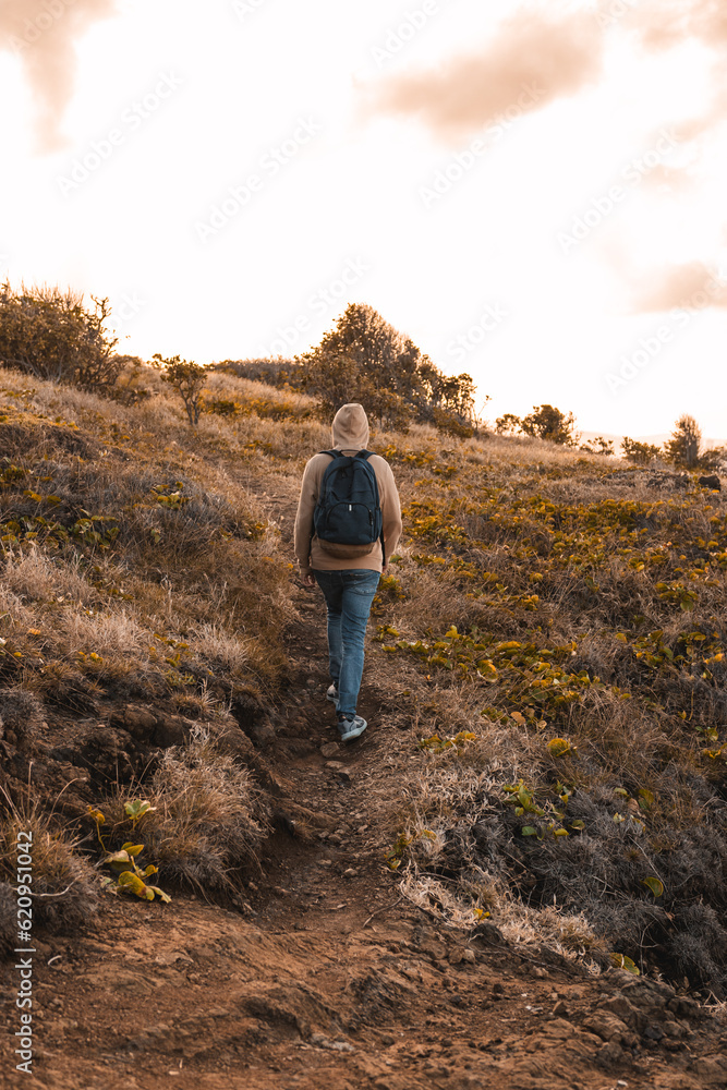 A man walking portrait carrying a dark blue bag pack on dry grass golden hour sunset from puerto rico A man walking portrait carrying a dark blue bag pack on dry grass golden hour sunset from puerto rico
