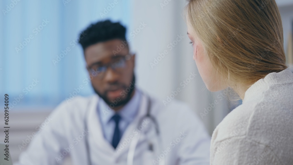 Obraz premium Caring African American doctor consulting injured woman, traumatologist office