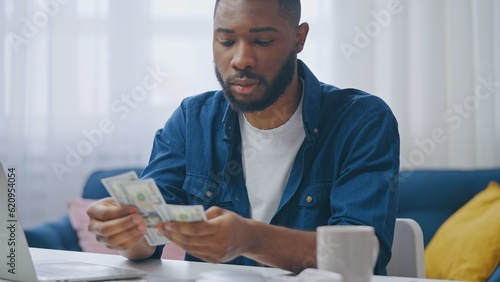 African American man counting money  satisfied with salary  saving for a dream