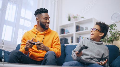 Tablou pe pânză Happy brothers having fun playing video games at home, leisure time, gaming hobb