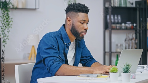 Young man working on a project on laptop, IT specialist, freelancer working from home