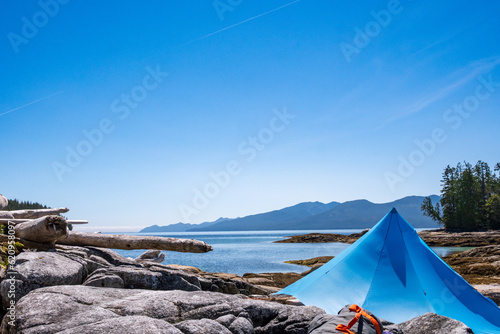  Blue tent on a beach  scenic vista of ocean and mountains in the back ground on Fitz Hugh Sound during a summer kayak expedition Inland Passage  Hieltsukl Territory  Central Coast  British Columbia
