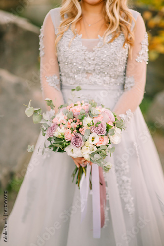 happy bride woman. closeup female hands holding wedding creative bouquet white purple rose flowers berries eucalyptus plant bridal white gray dress. Girl blonde hair. autumn nature forest green trees