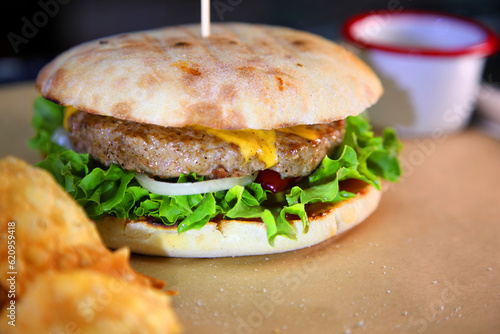 Burger with meat and vegetables. Hot burger in a burning sauce.