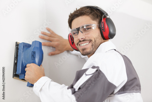 professional construction worker using sander on interior wall photo