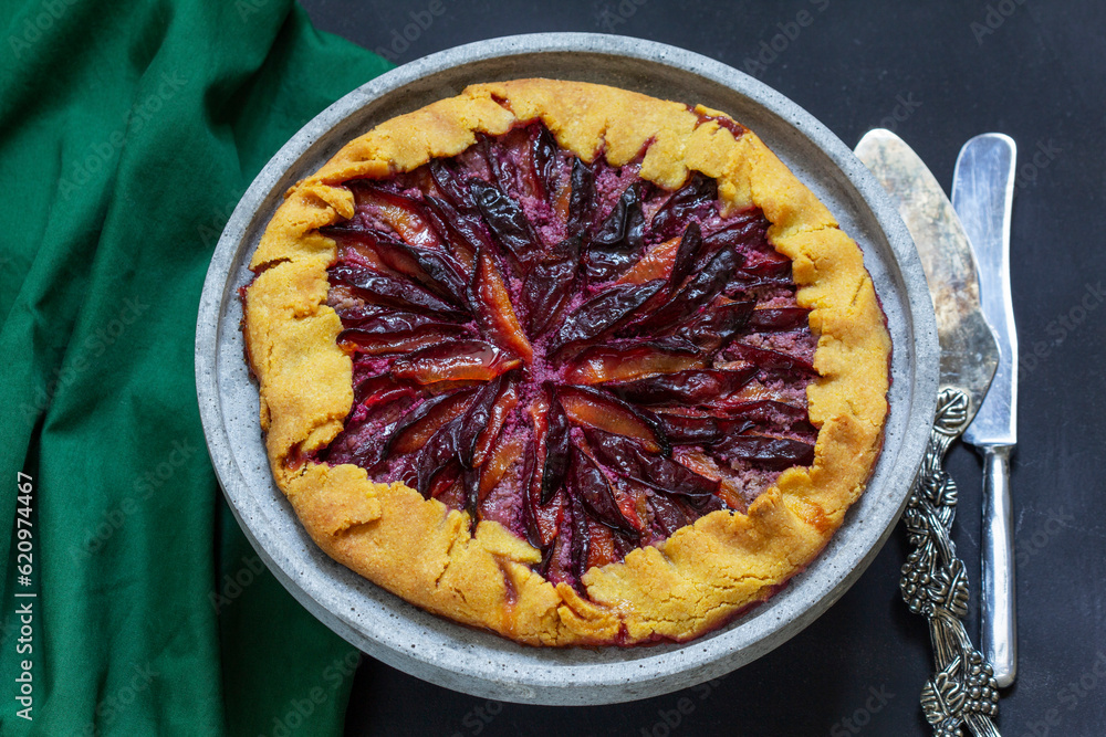 Traditional french pie galette made of corn dough with plum filling on a concrete tray.