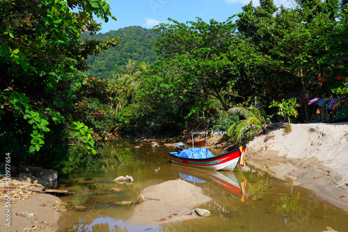 Small fishing boat on a creek coming out of the jungle on Khlong Chak Beach, Koh Lanta Yai island, Krabi province, Thailand