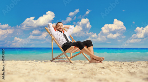 Man in a shirt and pants resting on the beach by the sea