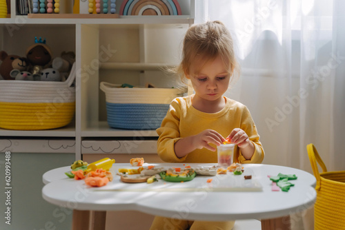A little girl playing with rainbow from play dough for modeling with decorate from dried beans. Art Activity for Kids. Fine motor skills. Sensory play for toddlers.