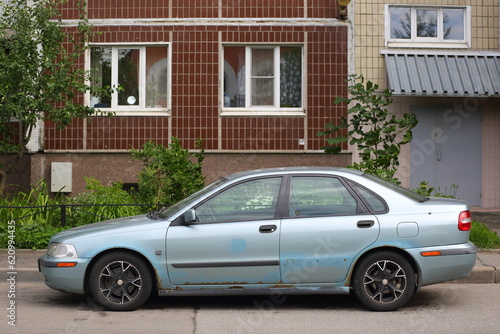 An old rusty light car is parked near a residential building, Iskrovsky Prospekt, Saint Petersburg, Russia, July 07, 2023 © Станислав Вершинин