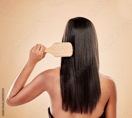 Back of woman, brush and hair care in studio, background and grooming of smooth texture. Beauty, growth shampoo and female model with comb tools for aesthetic hairstyle, keratin treatment and shine