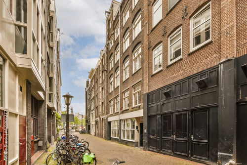 some bikes parked on the side of a street in an urban area with tall brick buildings and red doord windows photo
