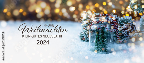Christmas greeting card with German text Frohe Weihnachten und ein gutes neues Jahr 2024 - Beautiful xmas decoration with Christmas tree in snow - Background banner