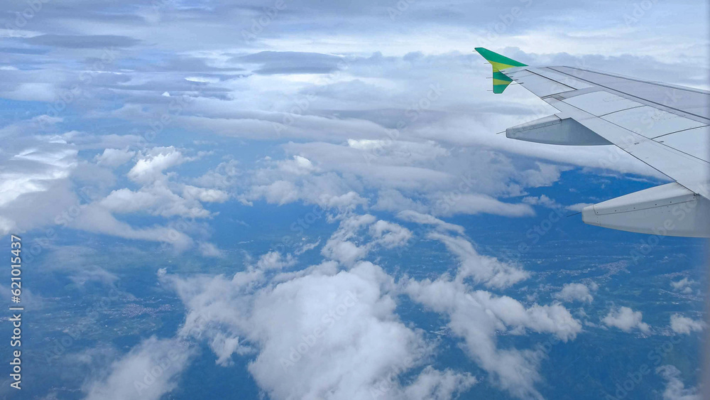 Fototapeta premium Green plane wing view from window with clouds and sea
