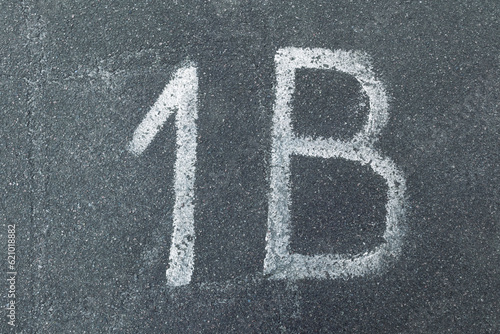The inscription "1B" on gray rough asphalt