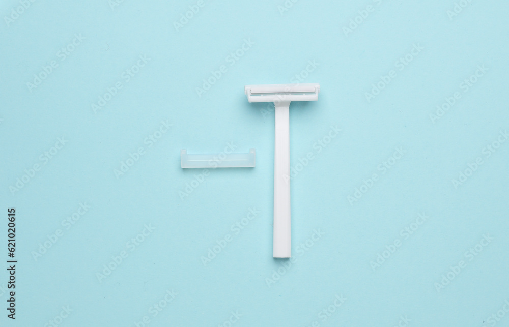 Disposable white plastic razor on blue background. Top view Disposable white plastic razor on blue background. Top view
