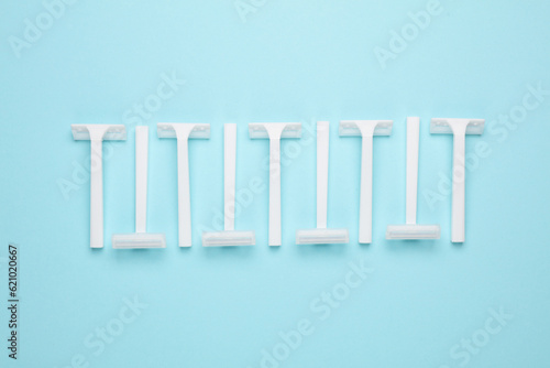 Disposable white plastic razors on blue background. Top view. Creative layout