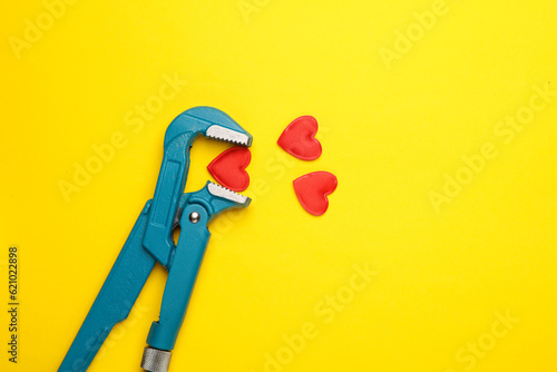 Adjustable wrench with hearts on a yellow background. Love, romantic concept photo