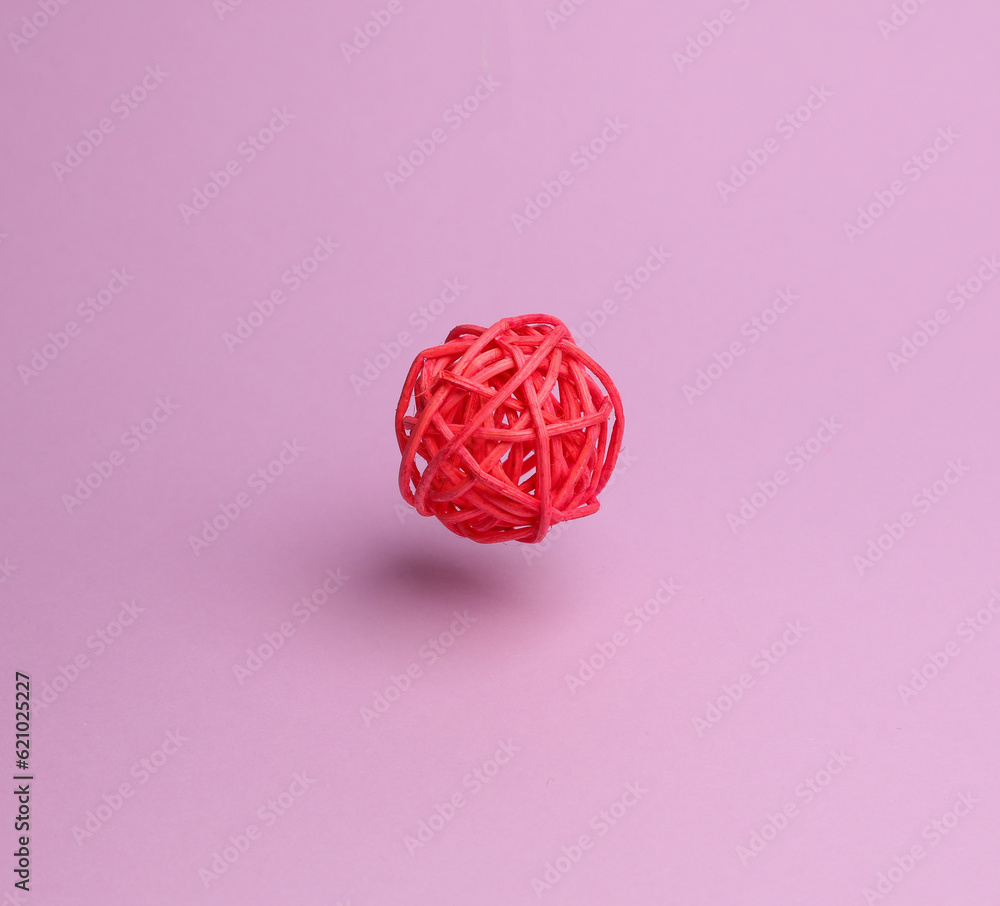 Wicker red wooden ball toy for a cat on a pink background Wicker red wooden ball toy for a cat on a pink background