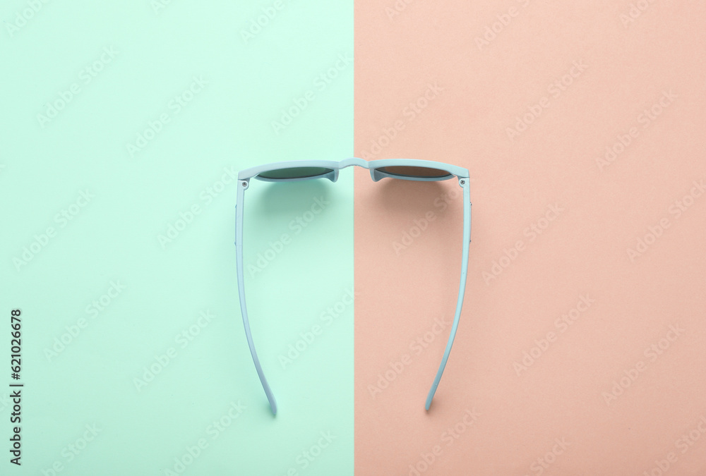 Top view stylish sunglasses on blue pink pastel background Top view stylish sunglasses on blue pink pastel background