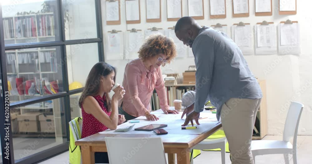 Busy diverse architects discussing blueprints on table in office, slow motion Busy diverse architects discussing blueprints on table in office, slow motion
