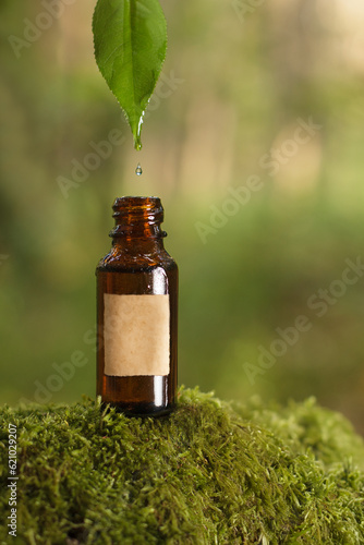 Oil drops entering a bottle on a green background, empty label. Mockup.