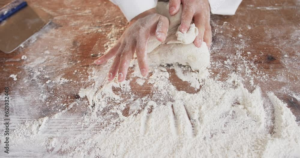 Asian female baker working in bakery kitchen, kneading dough on counter in slow motion Asian female baker working in bakery kitchen, kneading dough on counter in slow motion