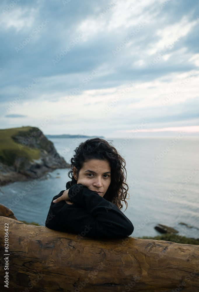 Young woman thinking while sitting on a bench on the beach Young woman thinking while sitting on a bench on the beach