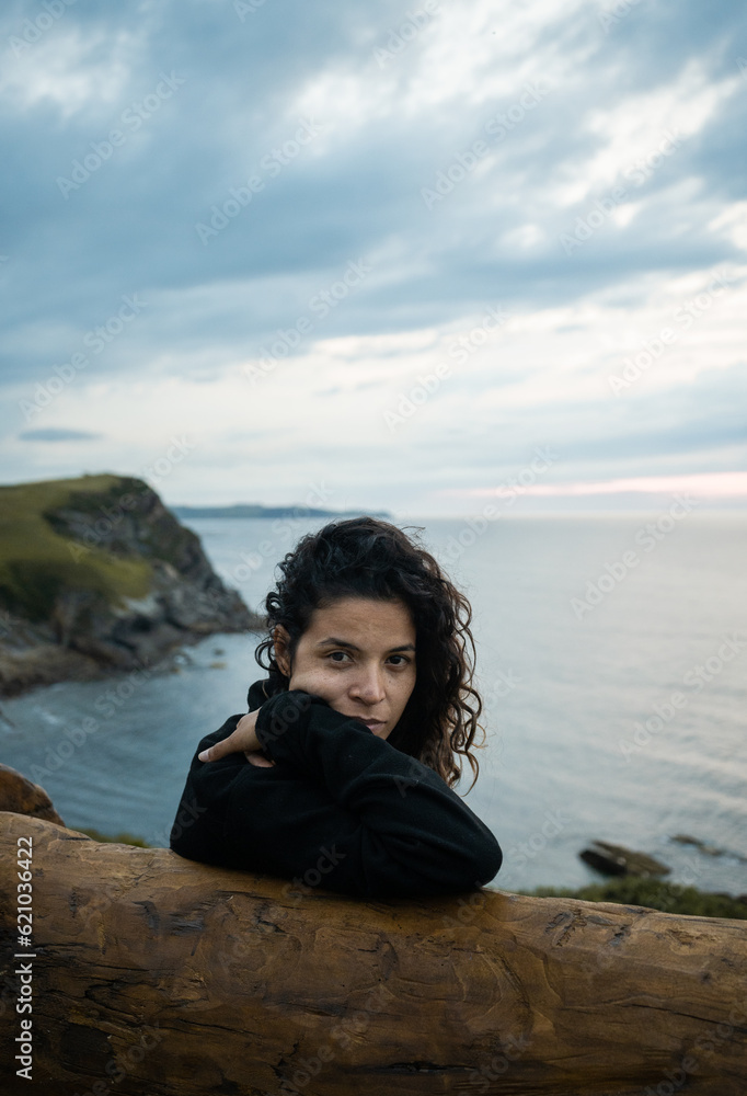 Young woman thinking while sitting on a bench on the beach