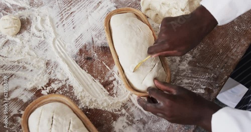 Wallpaper Mural African american male baker working in bakery kitchen, cutting dough for bread in slow motion Torontodigital.ca