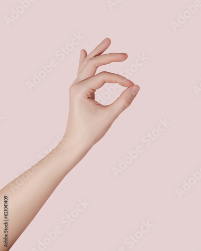 Female hand making ok sign on pink background.