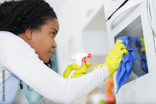 Φωτογραφία woman cleaning oven with spray bottle and sponge