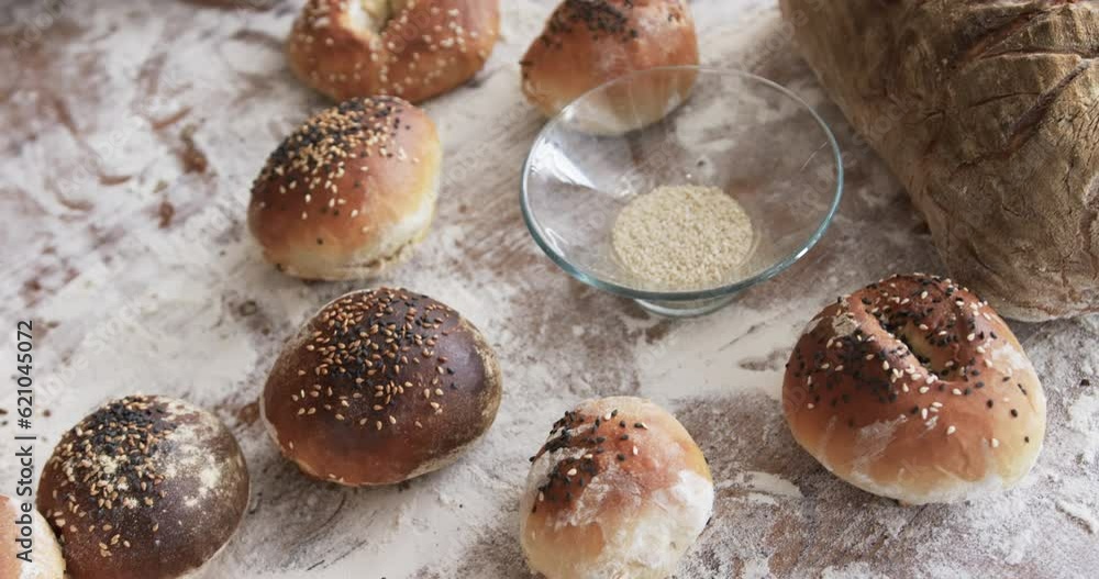 Close up of rolls, bread, flour and rolling pin on table in bakery kitchen, slow motion