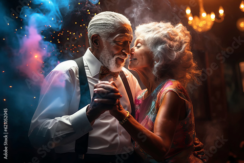 Stylish senior couple dancing at a party. Festive bokeh background
