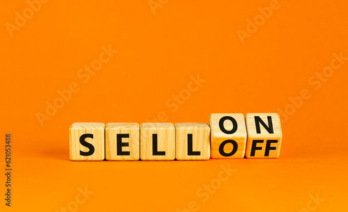Sell on or off symbol. Businessman turns wooden cubes and changes word Sell off to Sell on. Beautiful orange table orange background. Business and sell on or off concept. Copy space.