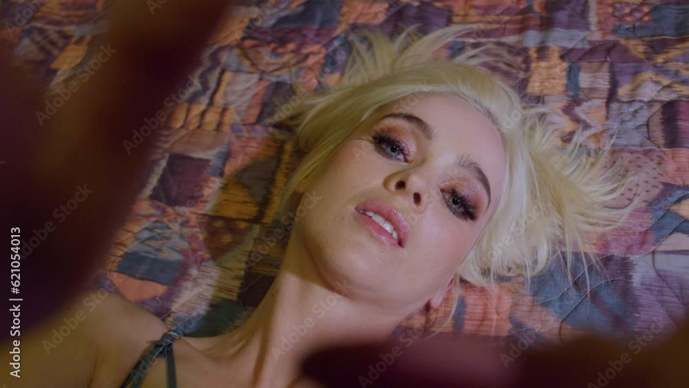 POV angle of a woman laying on an older motel bed wearing lingerie