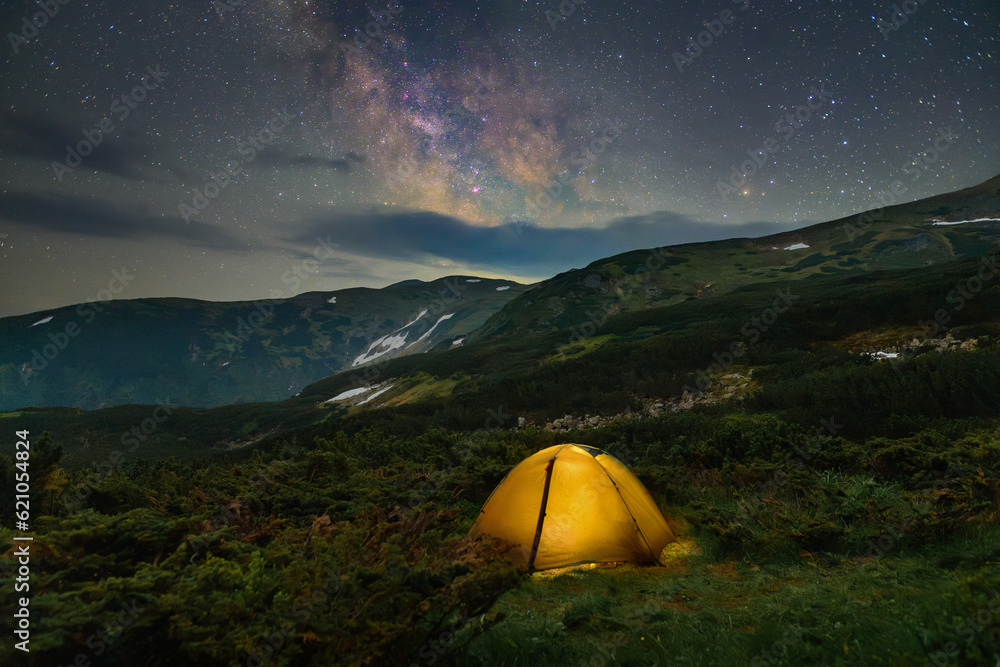 Atmospheric photo of a tourist tent in the mountains under the stars and the milky way