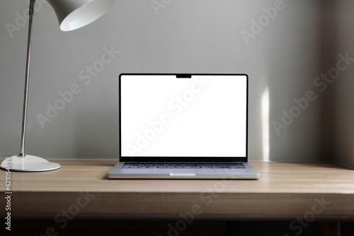 laptop on the table with space for a signature. Macbook 14 pro 2021. gray wall, hotel workplace.copy space White lamp on the table