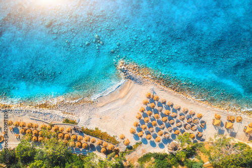 Fototapeta Naklejka Na Ścianę i Meble -  Aerial view of sandy beach with umbrellas, green forest at sunrise in summer. Blue lagoon in Oludeniz, Turkey. Tropical landscape with sea bay, island, white sandy bank, blue water. Top view. Nature
