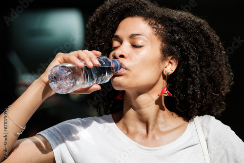 Head-shot of curly woman drinking still-water.
