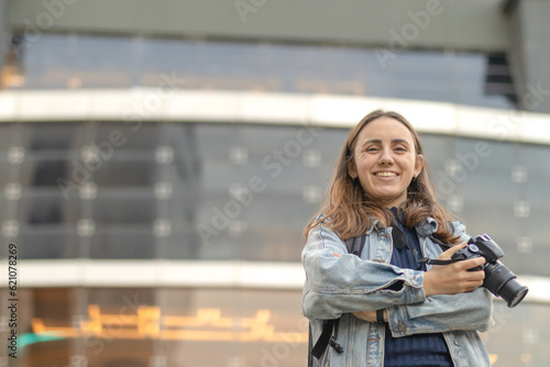 Woman photographer smiling with mirrored building in blurred background. Photography day concept. Copy space © martinkralicek