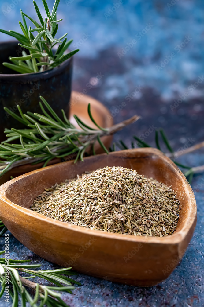 Fresh and chopped rosemary in a wooden bowl on a colored background Fresh and chopped rosemary in a wooden bowl on a colored background